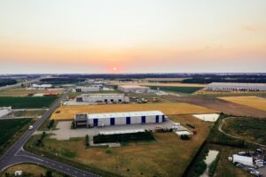 Aerial view of industrial warehouses in Poznań, Poland at sunrise, showcasing the landscape and architecture.